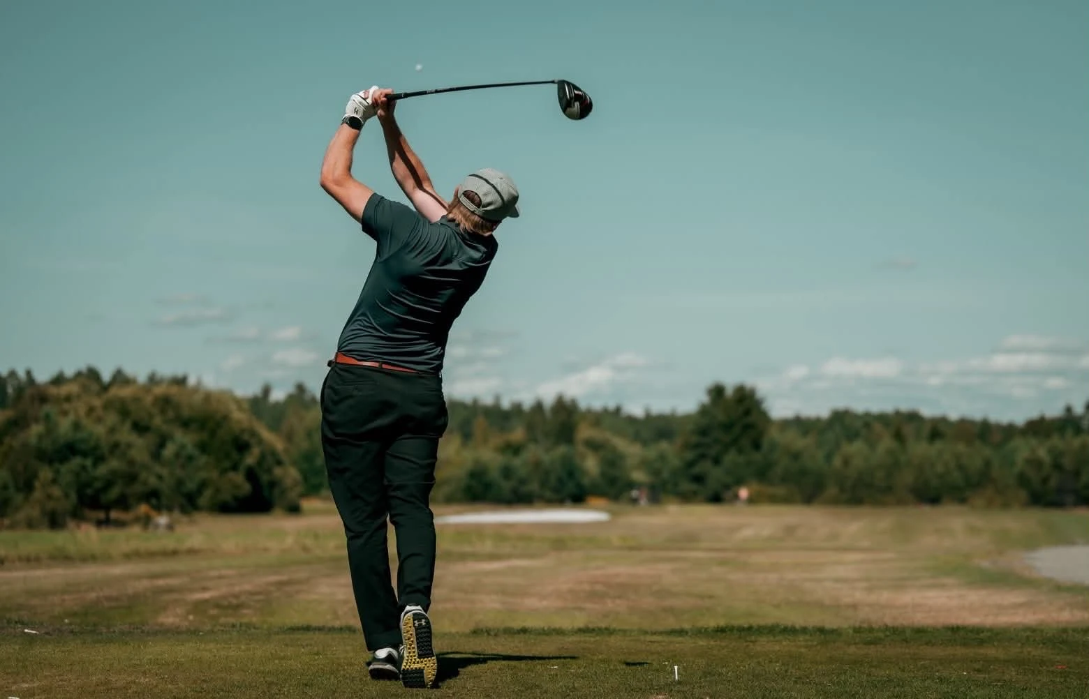 Golfare i Swinghard-piké avslutar en sving på golfbanan