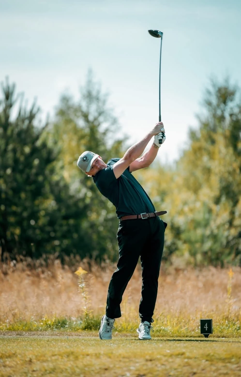 Golfare i mörk Swinghard-piké, med hela kroppen och klubban synliga i svingen